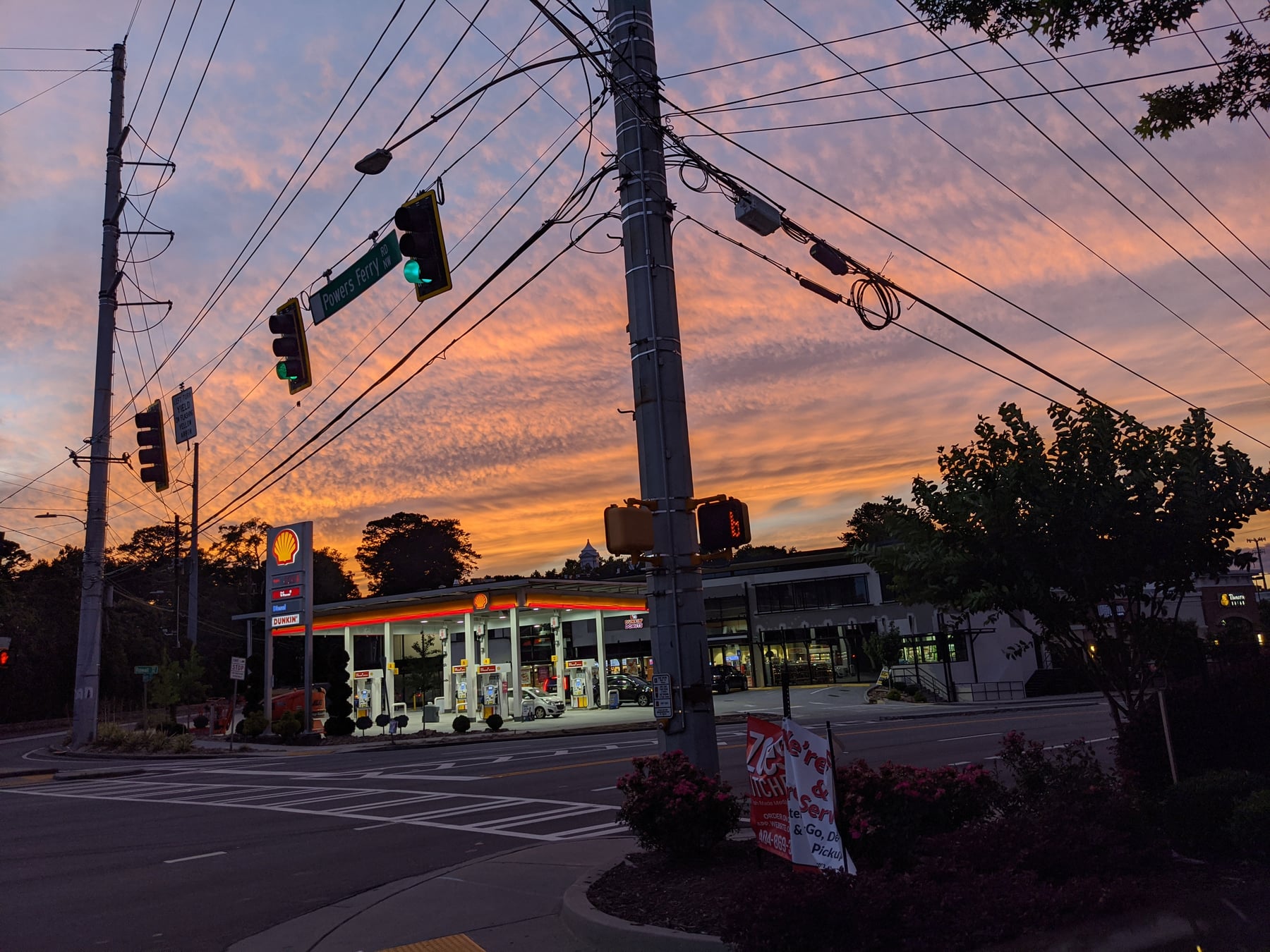 Shell gas station at sunset, power lines and traffic signals against vivid orange sky