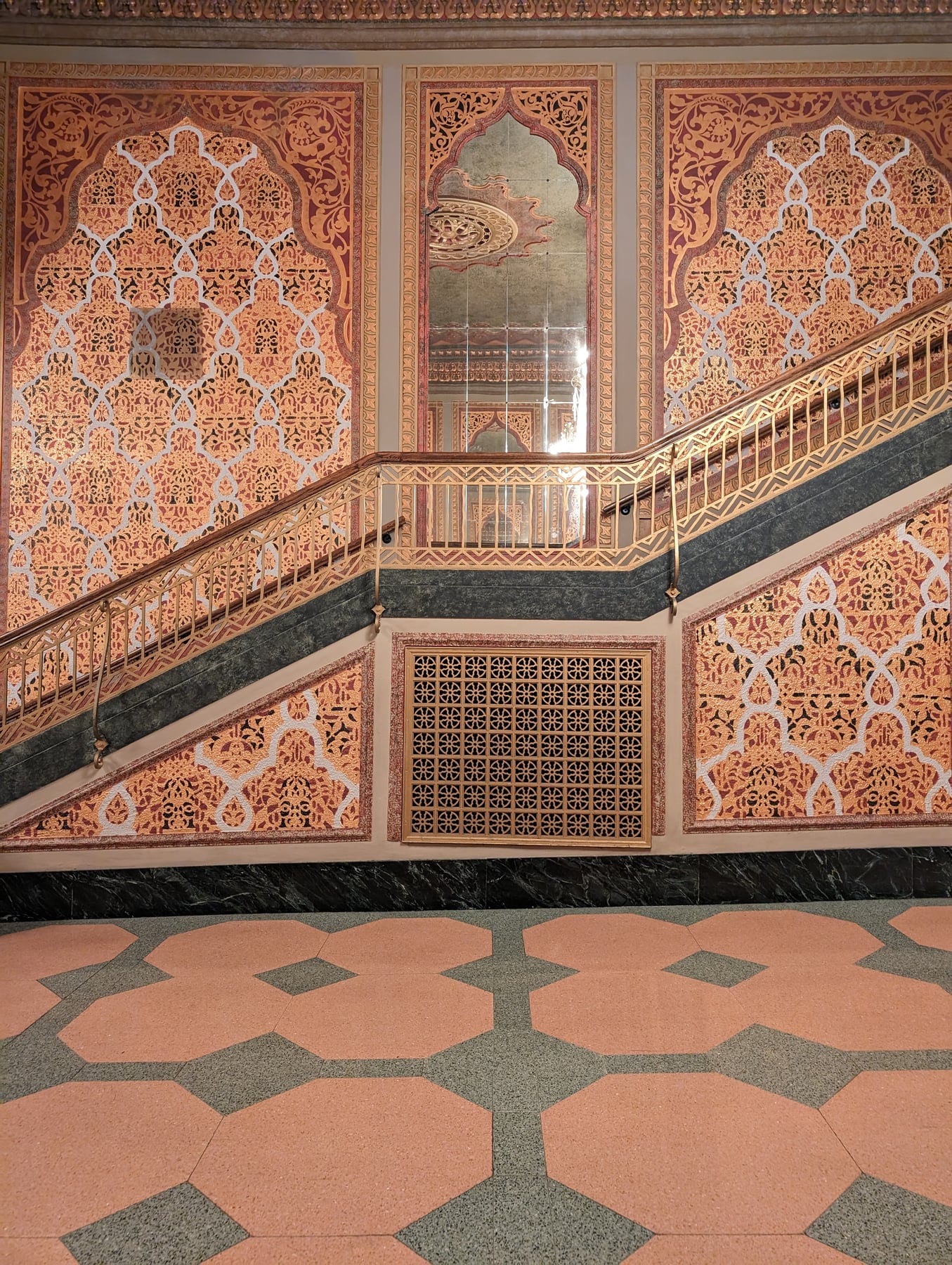 Moorish interior wall covered in dense terracotta arabesque plasterwork, geometric tiled floor